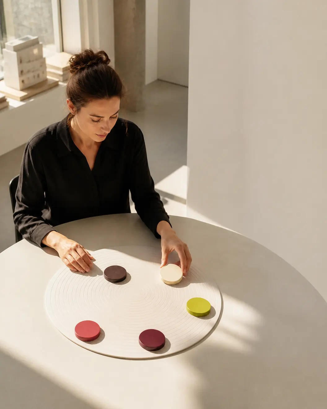 O persoană adultă aranjează cinci forme colorate pe o suprafață circulară de lucru